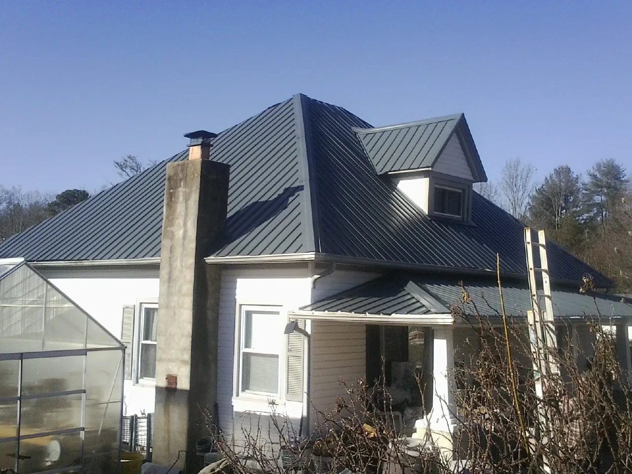 Dark blue standing seam metal roof on a white farmhouse with dormer — Slate & Tile Roof Repair by Roofing Brothers in Mc Adenville