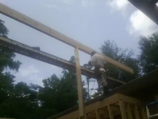 Carpenter setting a ridge beam over a new addition frame — Ice Dam Removal by Roofing Brothers in Mc Adenville