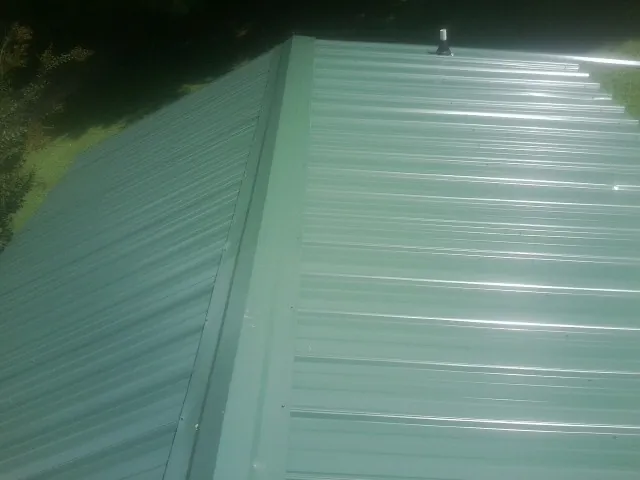 New green metal panels meeting at the ridge of a roof — Flat Roof Repair work by our crew in Mc Adenville