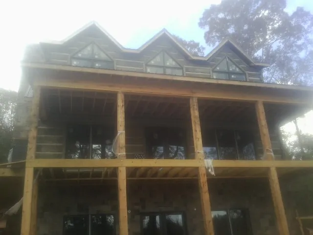 Dormers and porch framing on a large log home under construction — Roof Coating work by our crew in Mc Adenville