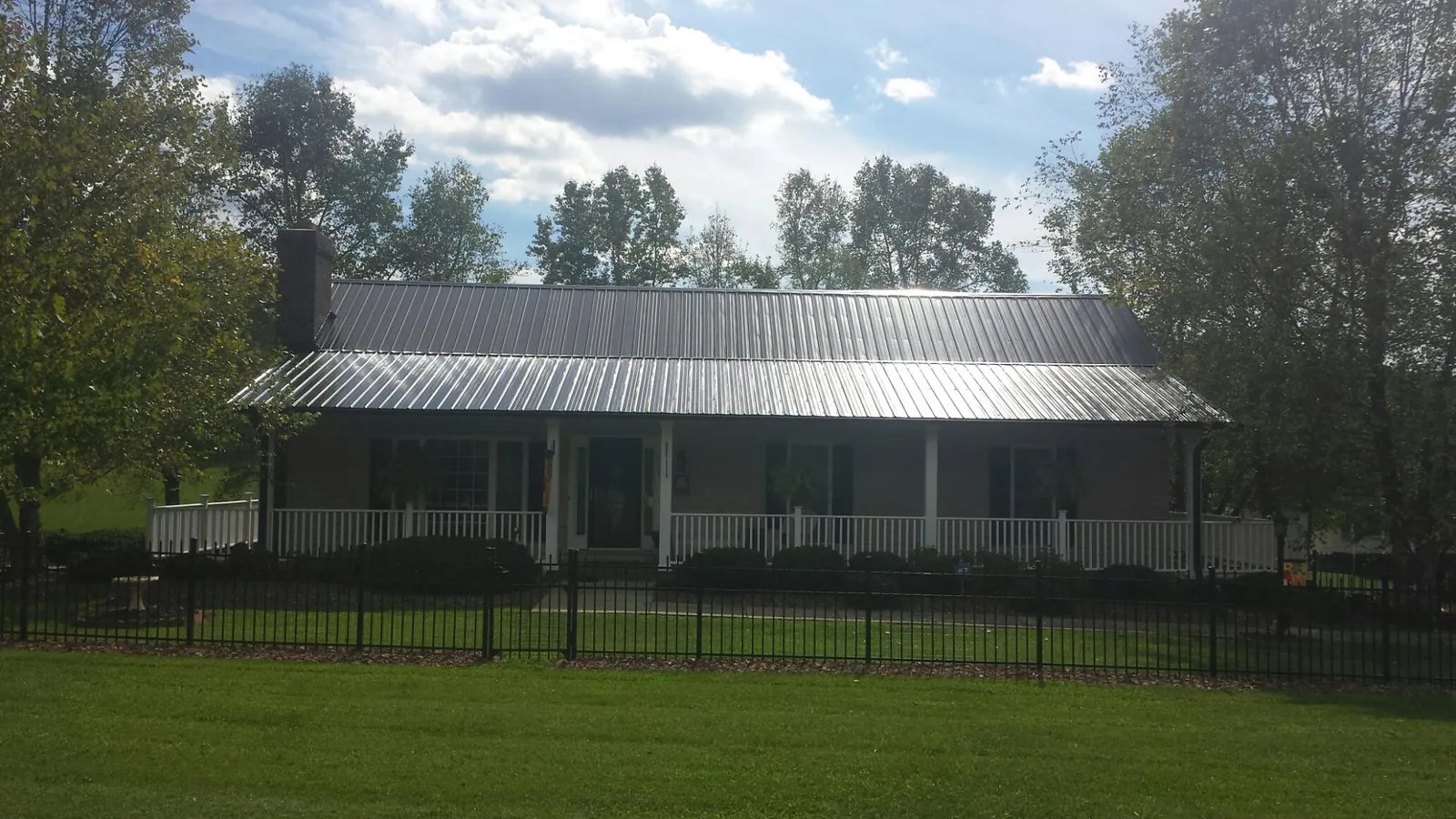 Gray metal roof on a brick ranch with a full width front porch — Gutter Guard Installation work by our crew in Mc Adenville
