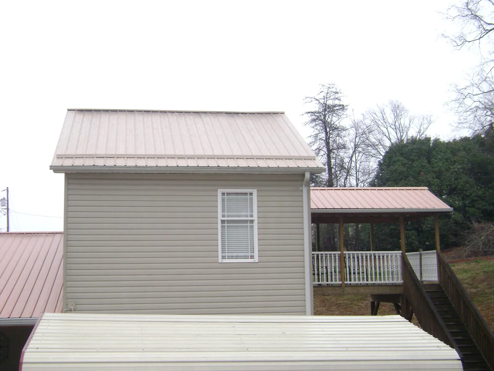 Tan metal roofs on a two story addition and attached porch, from a Roof Replacement job in Mc Adenville