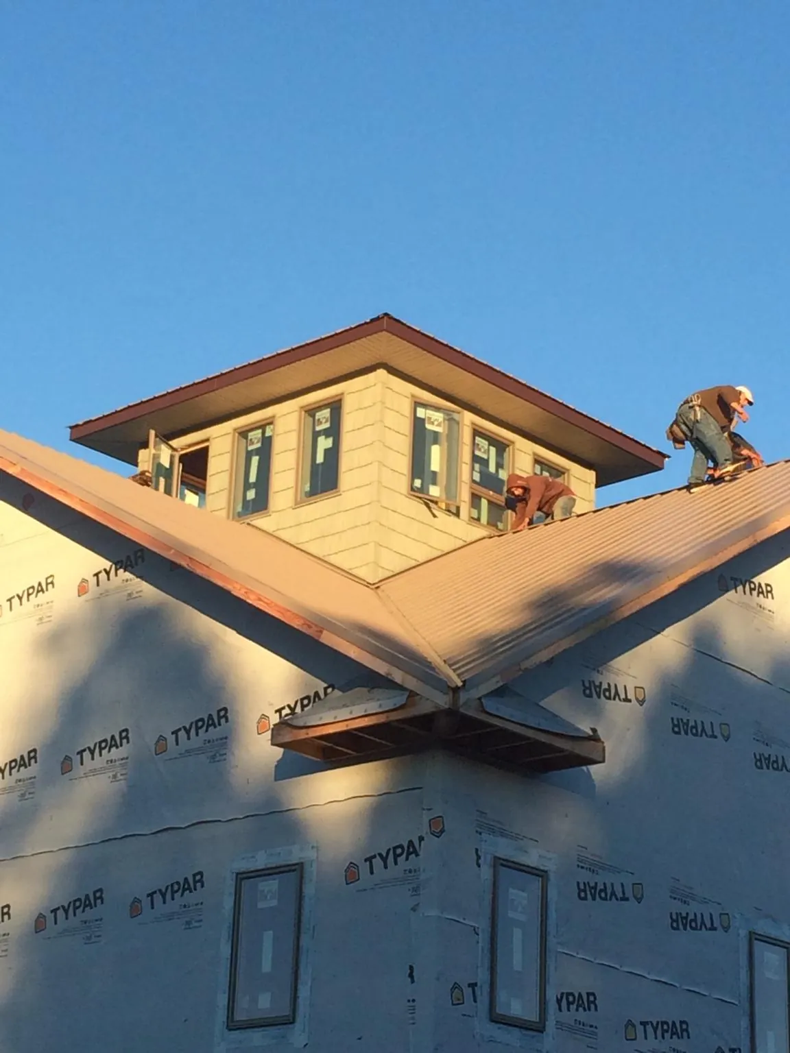 Roofers working around a rooftop cupola on a new metal roof at sunset — Roof Waterproofing in Mc Adenville by Roofing Brothers